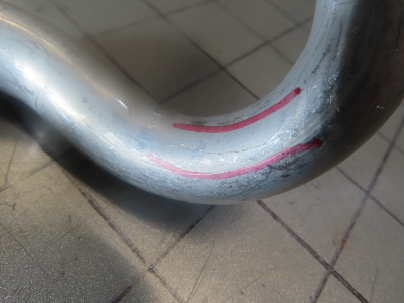 Close-up of an aluminum tube test specimen with markings and a longitudinal crack